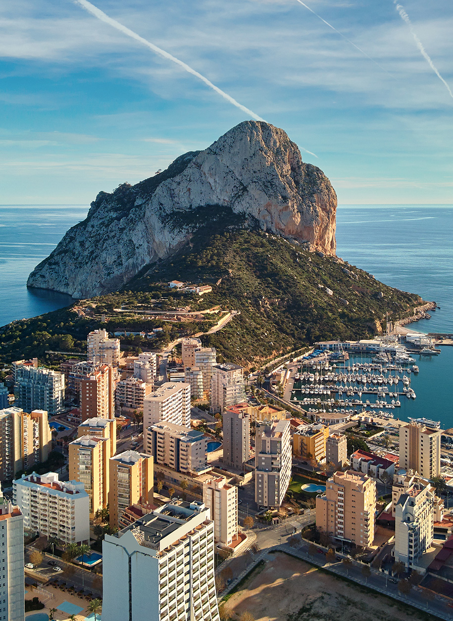 Drone point of view Rock of Penon de Ifach, harbor, Mediterranean sea rooftops of houses Calp cityscape. Coastal town located in comarca of Marina Alta province of Alicante Valencian Community, Spain